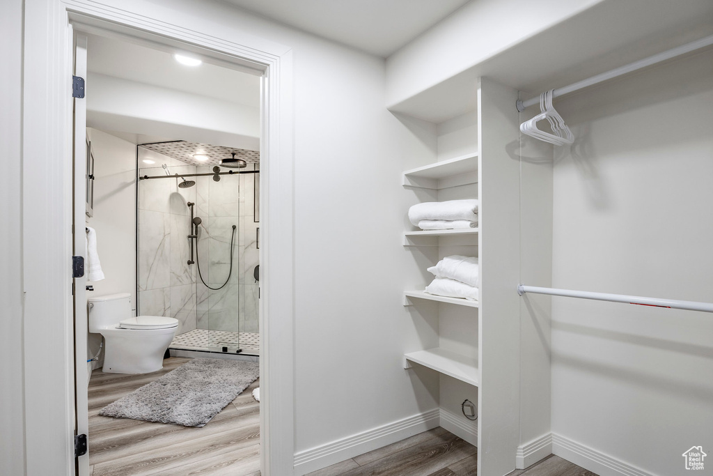 Interior space featuring hardwood / wood-style floors, a shower with door, and toilet