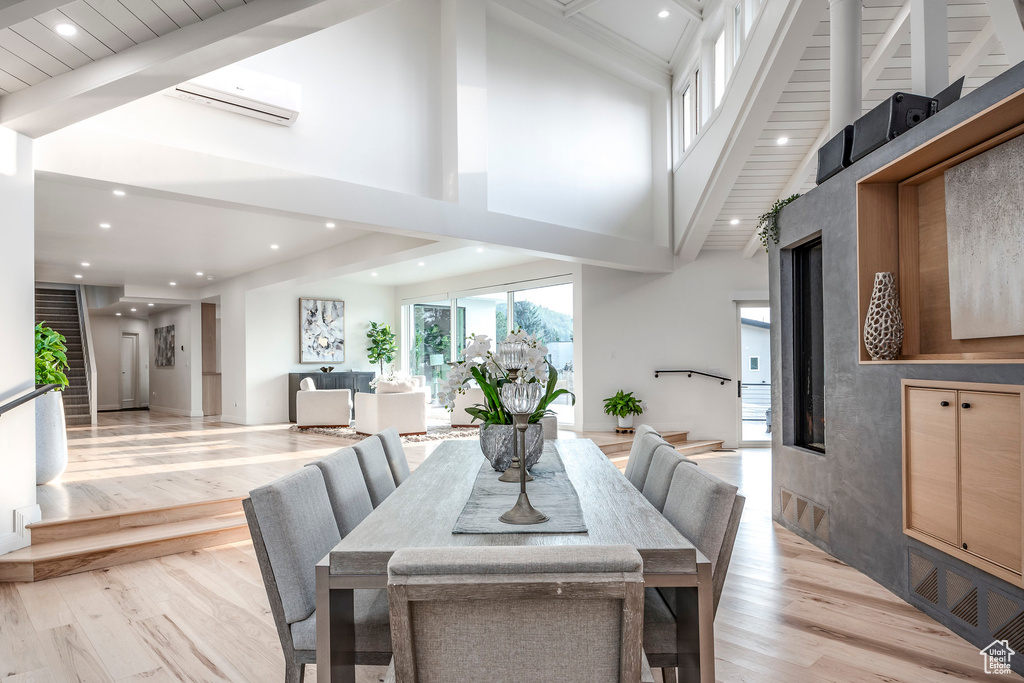 Dining space with light wood-type flooring, a high ceiling, and a wall mounted air conditioner