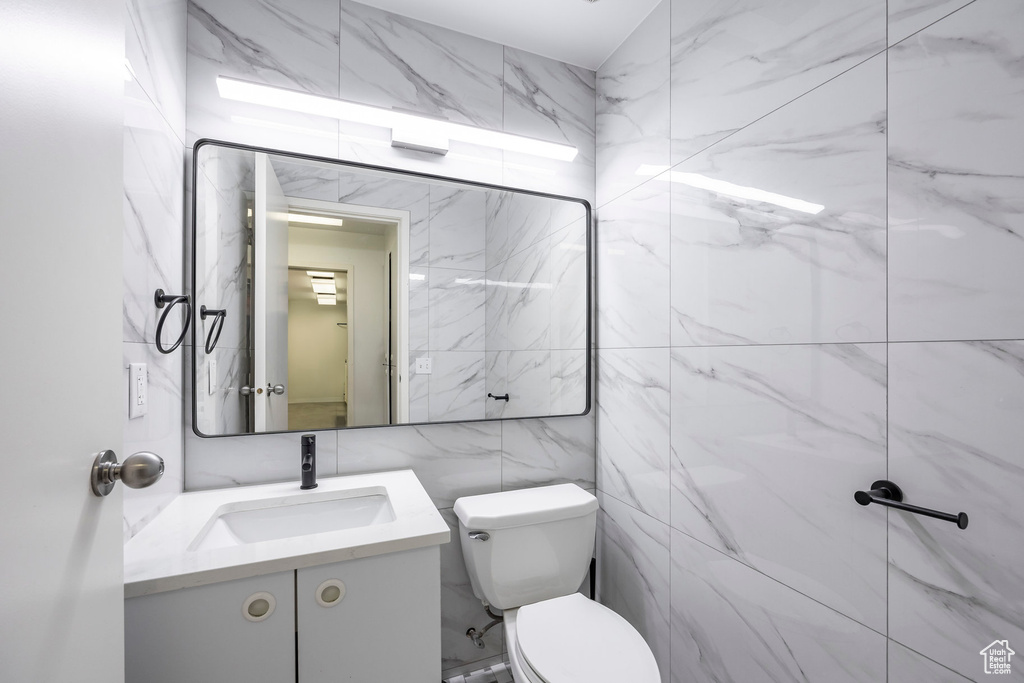 Bathroom featuring tile walls, vanity, and toilet