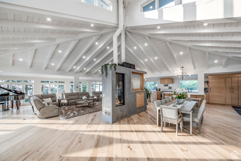 Living room with beamed ceiling, light hardwood / wood-style flooring, high vaulted ceiling, and a healthy amount of sunlight