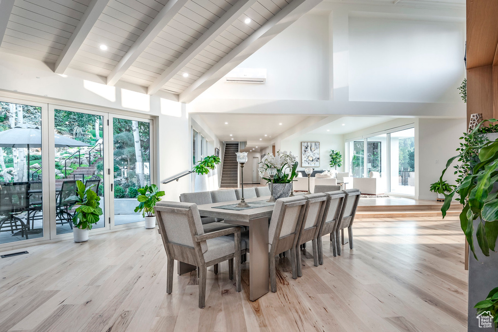 Dining room with high vaulted ceiling, beam ceiling, light hardwood / wood-style flooring, and a wealth of natural light