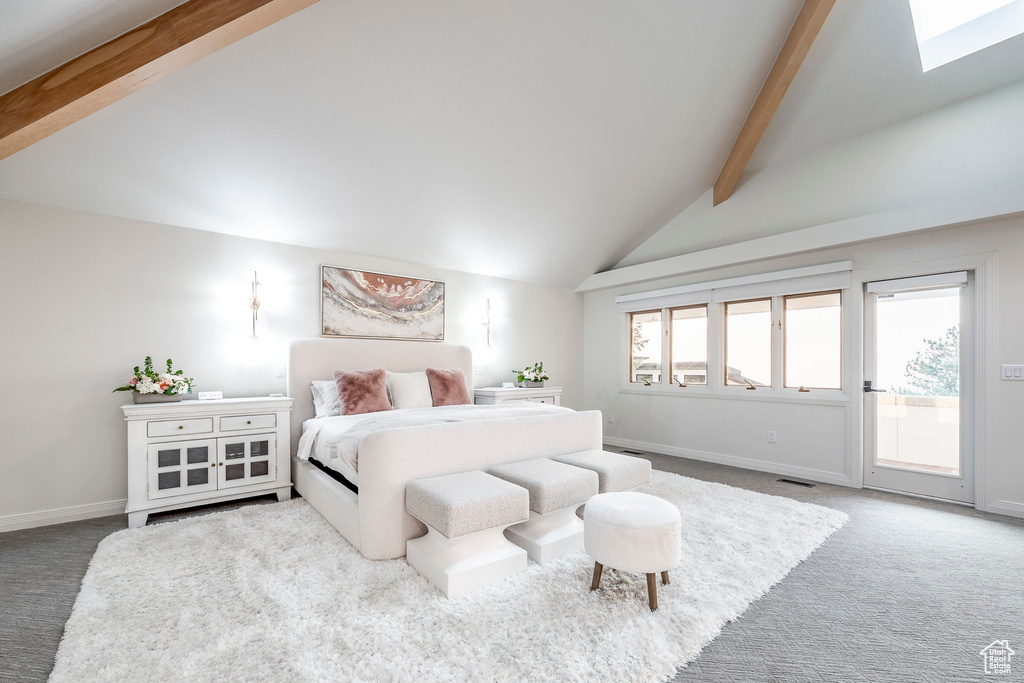 Carpeted bedroom featuring access to outside, a skylight, beam ceiling, and high vaulted ceiling