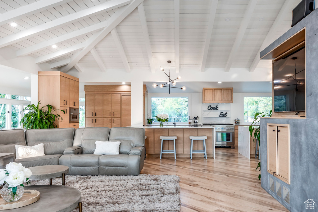 Living room with light wood-type flooring, vaulted ceiling with beams, and a notable chandelier