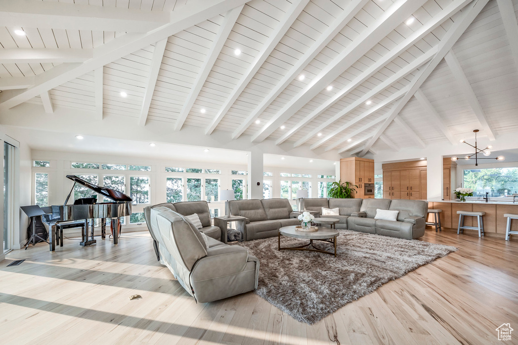 Living room featuring light wood-type flooring, beam ceiling, high vaulted ceiling, and a notable chandelier