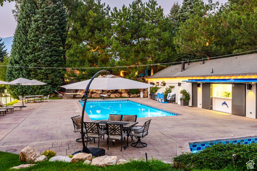 Pool at dusk featuring a patio area