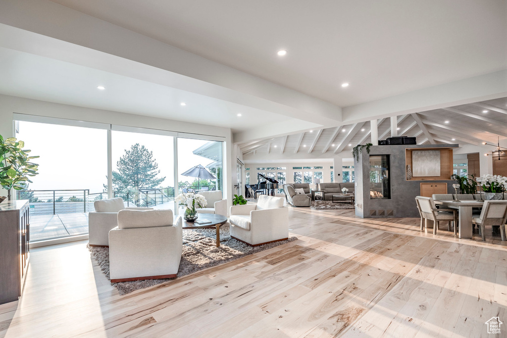 Unfurnished living room with vaulted ceiling with beams and light hardwood / wood-style flooring