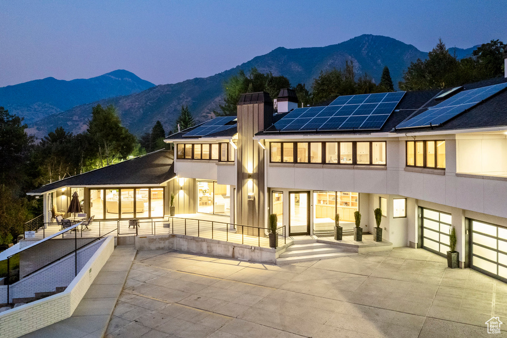 View of front facade with a balcony, a mountain view, a patio area, and solar panels