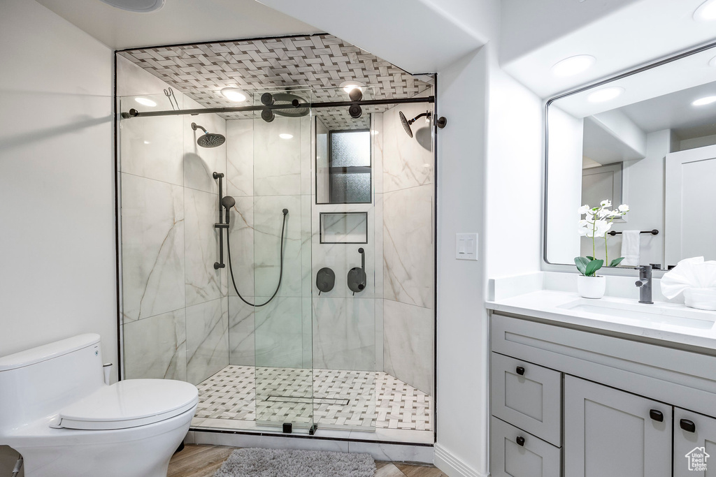 Bathroom featuring hardwood / wood-style floors, a shower with shower door, vanity, and toilet