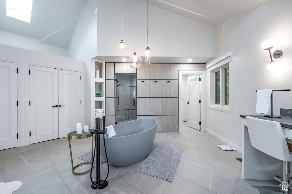 Bathroom featuring separate shower and tub, a skylight, and high vaulted ceiling