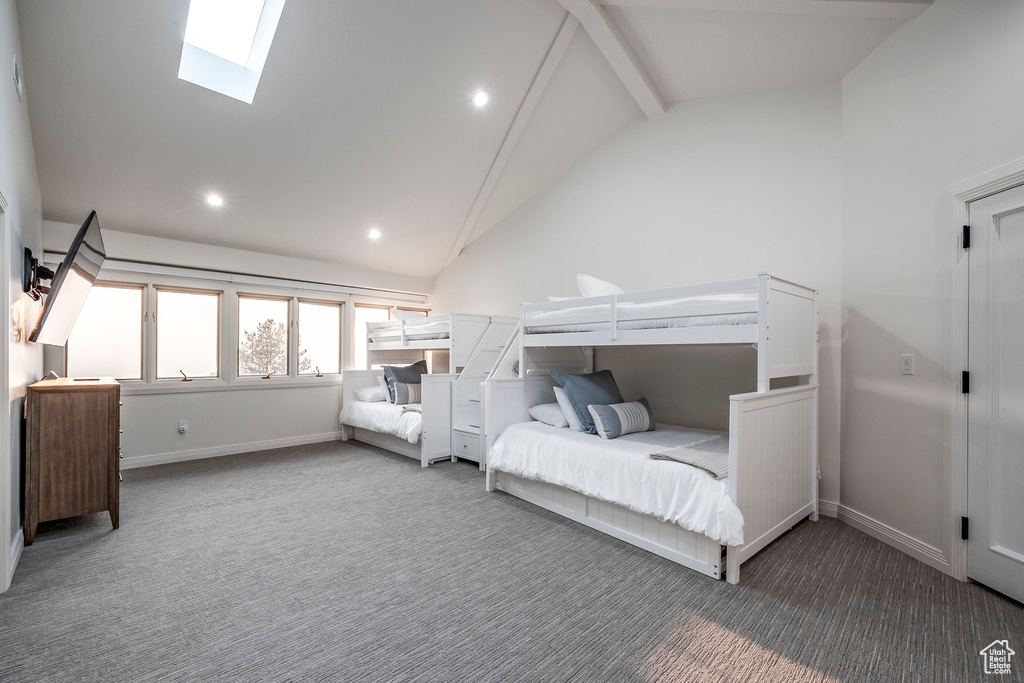 Bedroom with carpet floors, beam ceiling, a skylight, and high vaulted ceiling