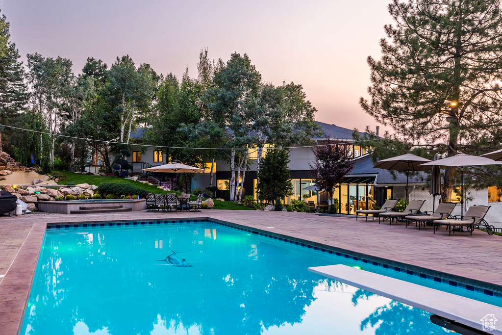 Pool at dusk with a patio and a diving board