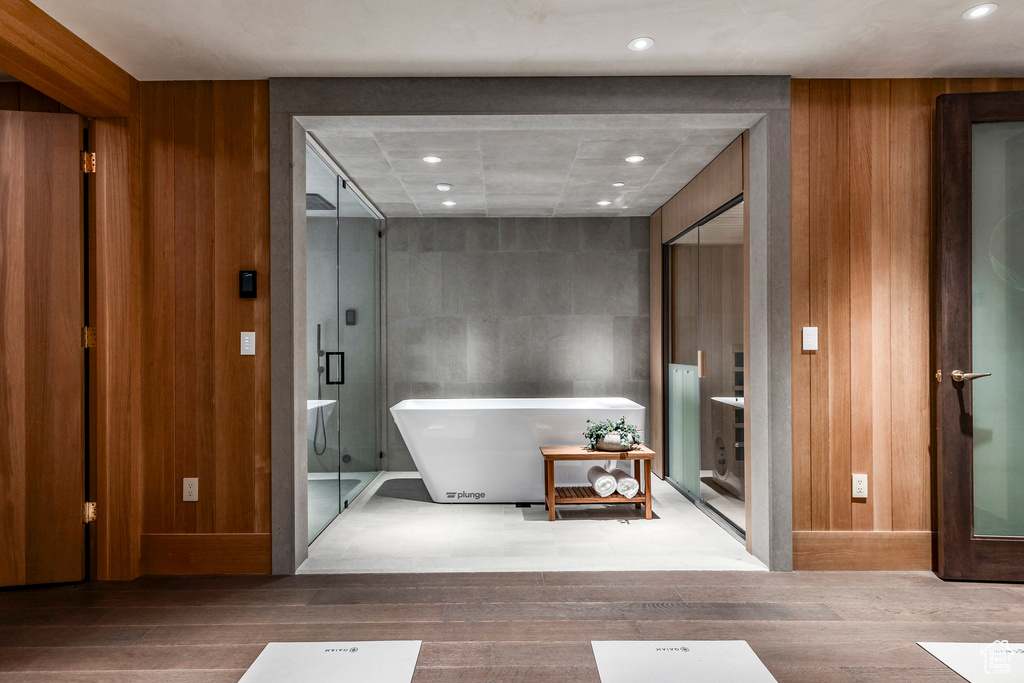 Bathroom featuring plus walk in shower, wood-type flooring, and wooden walls