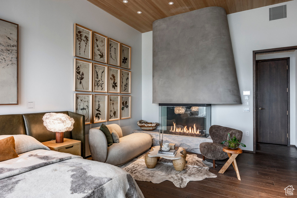 Bedroom with a multi sided fireplace, wooden ceiling, and dark wood-type flooring