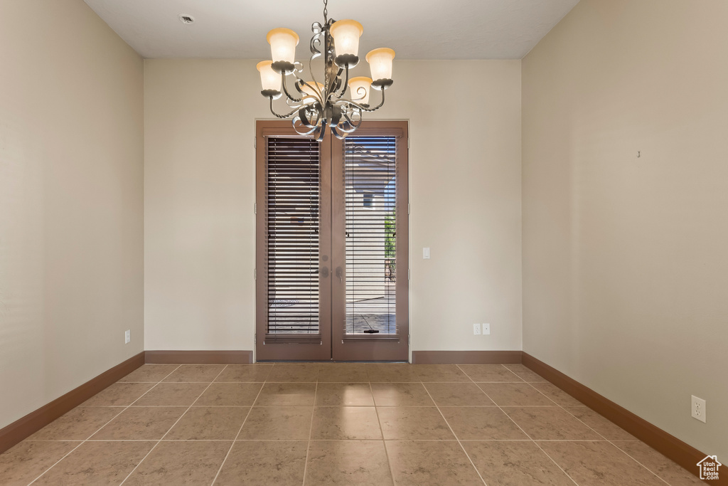 Empty room with tile patterned flooring and an inviting chandelier