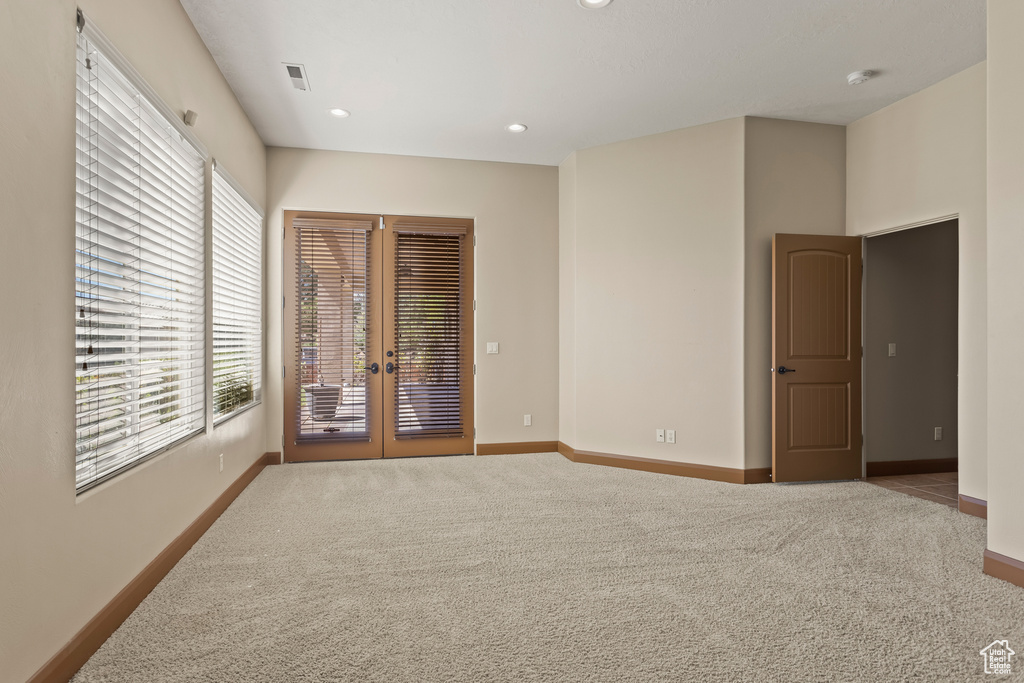 Unfurnished bedroom featuring light carpet and french doors