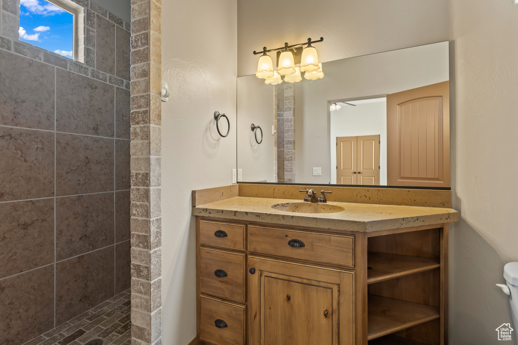 Bathroom featuring vanity, toilet, and tiled shower