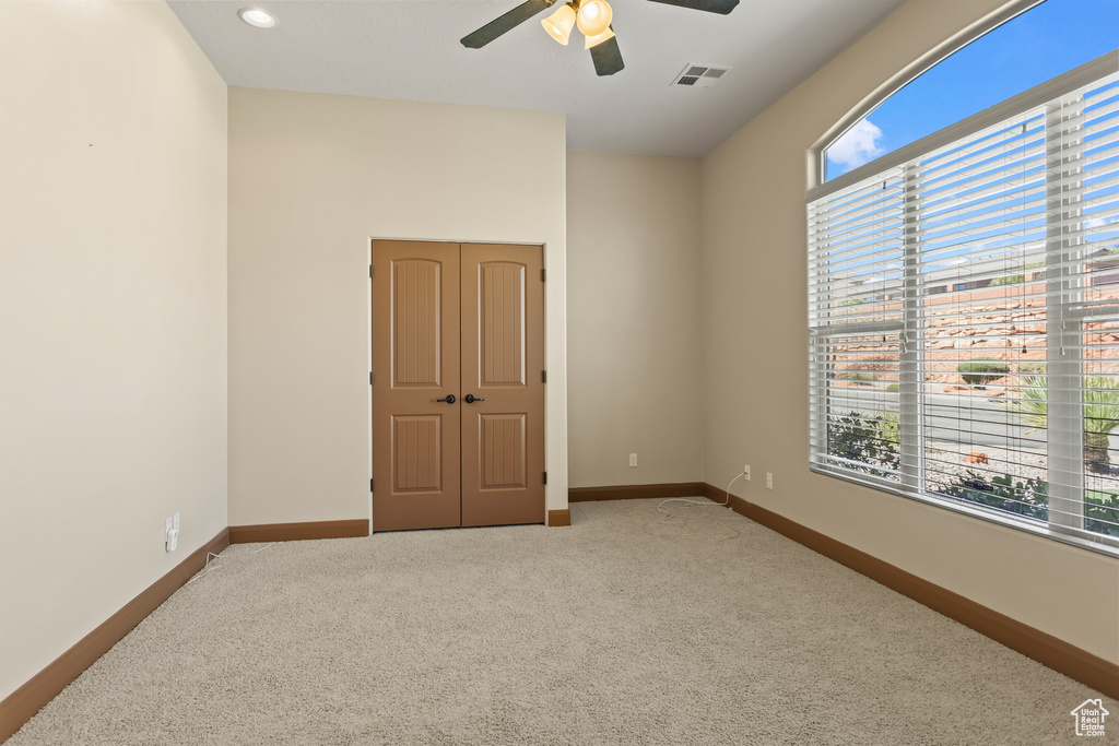 Unfurnished bedroom with carpet flooring, a closet, multiple windows, and ceiling fan