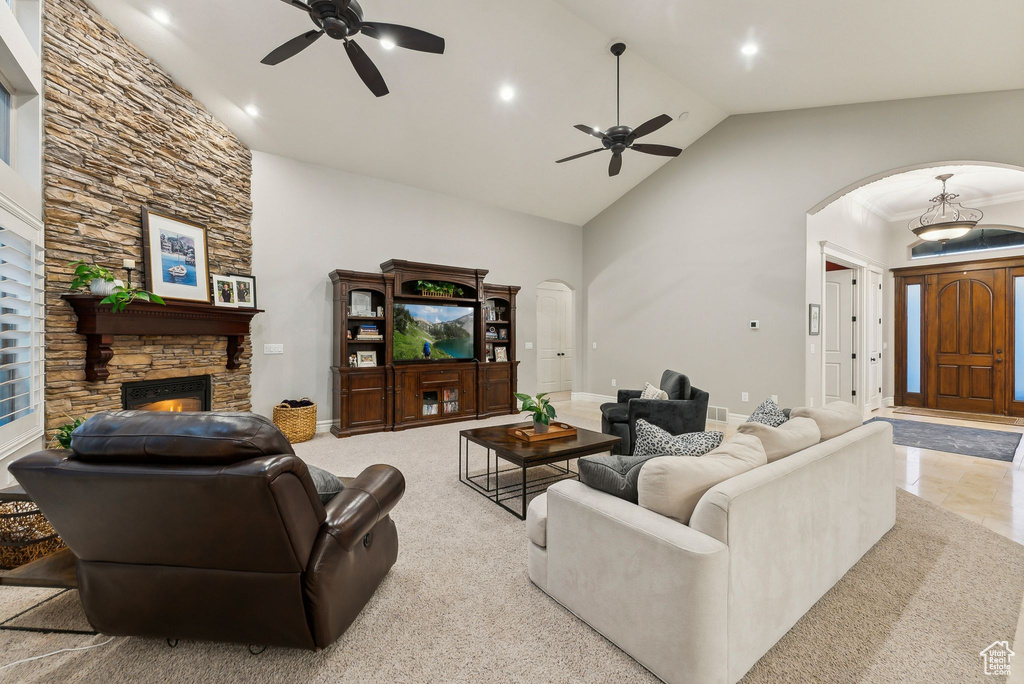 Living room with high vaulted ceiling, ceiling fan, light tile patterned floors, and a fireplace