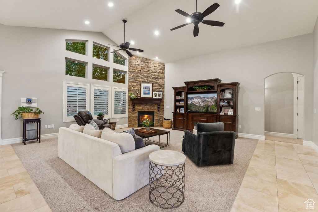 Living room with light tile patterned floors, a fireplace, ceiling fan, and high vaulted ceiling