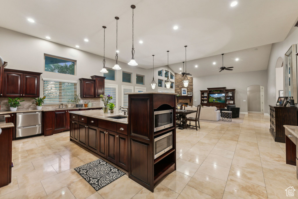 Kitchen with hanging light fixtures, a high ceiling, dark brown cabinetry, and ceiling fan