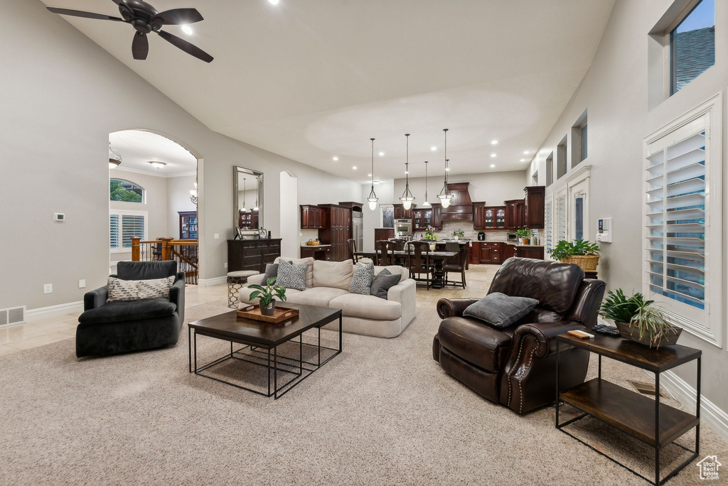 Carpeted living room with a high ceiling and ceiling fan