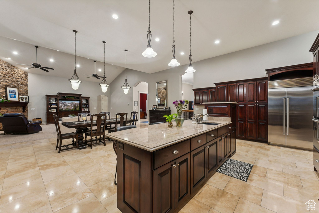 Kitchen with pendant lighting, a large island with sink, a fireplace, stainless steel built in fridge, and ceiling fan