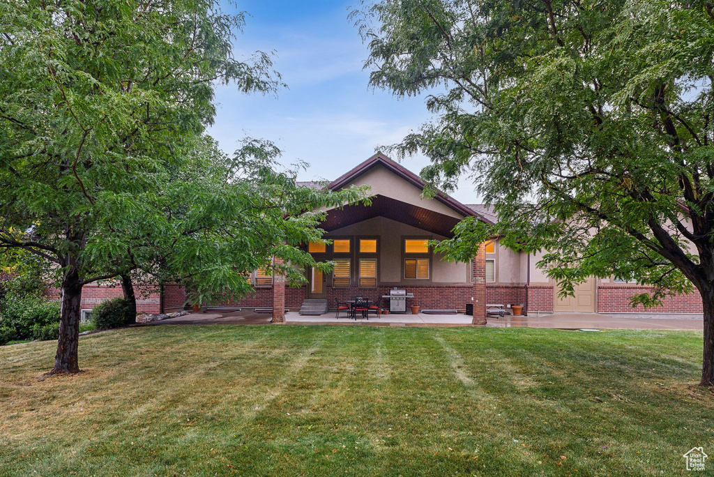 Back of house with a lawn and a patio