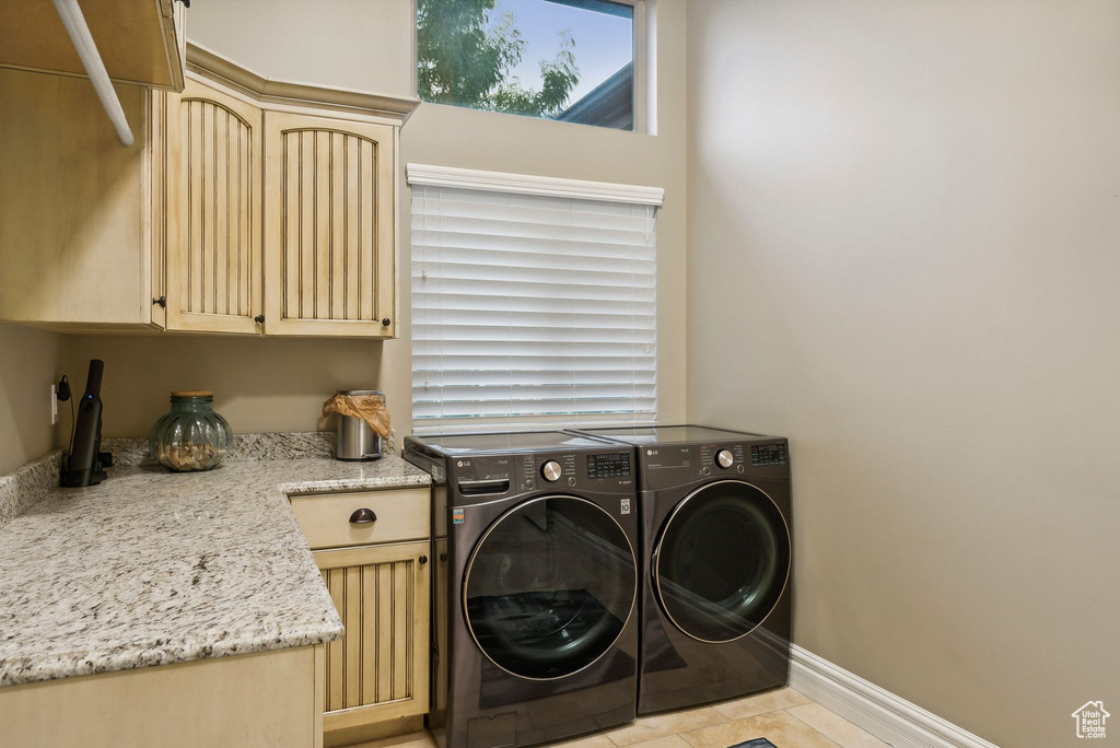 Washroom featuring cabinets, light tile patterned floors, and washer and dryer