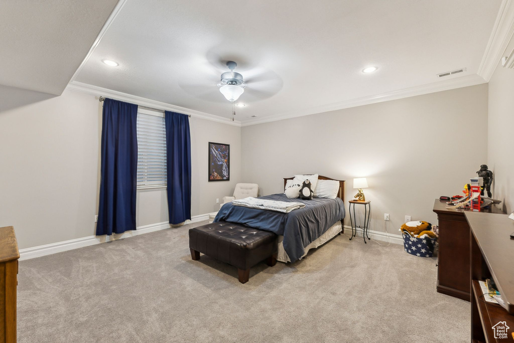 Carpeted bedroom with ceiling fan and crown molding