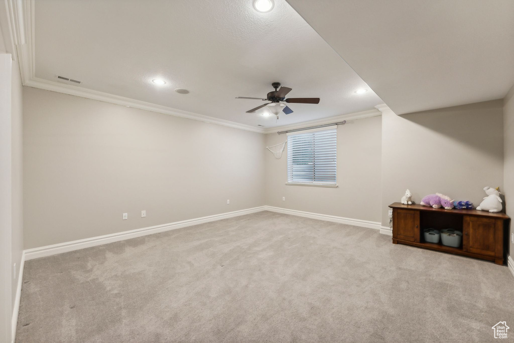 Spare room featuring ceiling fan, light colored carpet, and crown molding