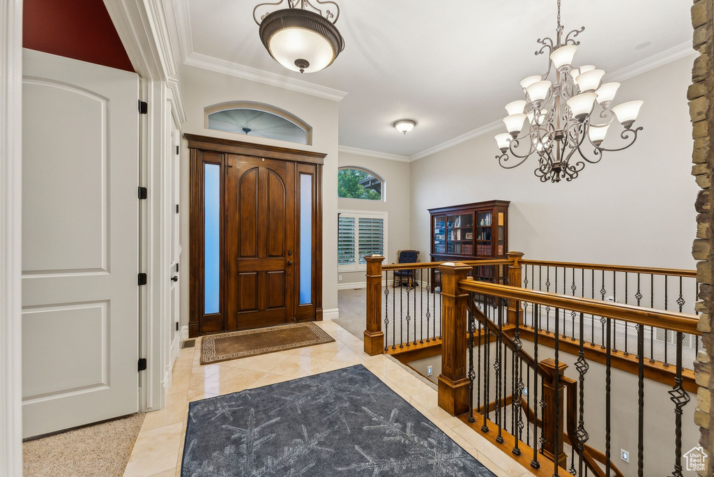 Tiled entrance foyer featuring an inviting chandelier and ornamental molding