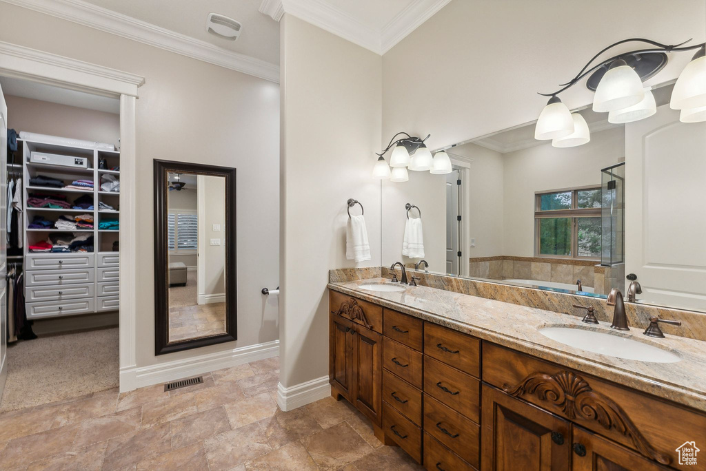 Bathroom with a shower with shower door, vanity, and crown molding