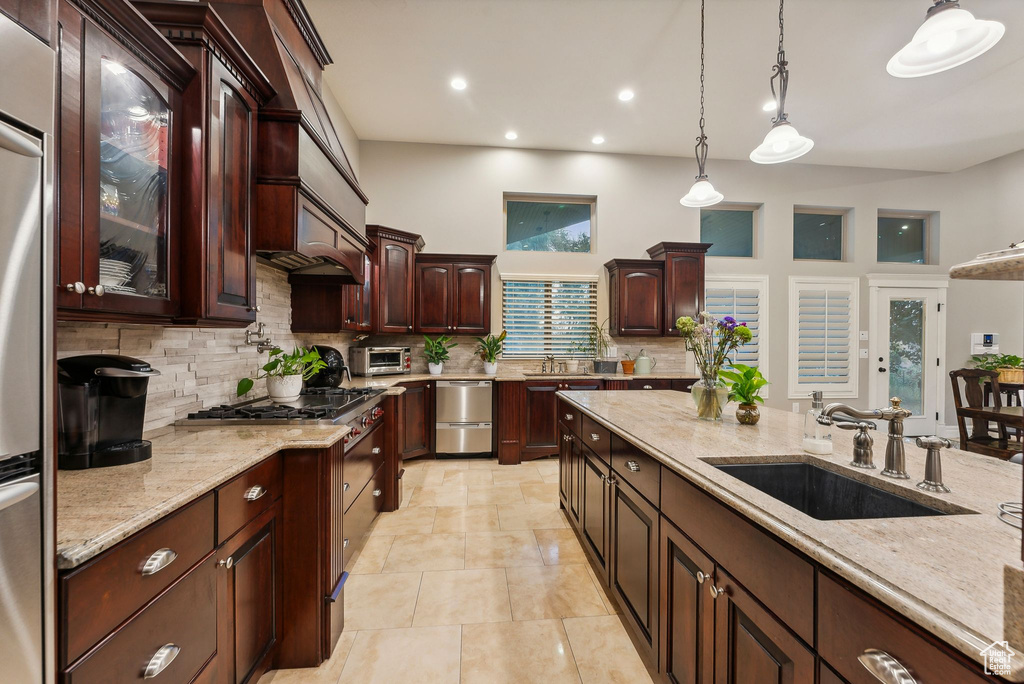 Kitchen featuring decorative backsplash, light stone countertops, decorative light fixtures, high end range, and sink