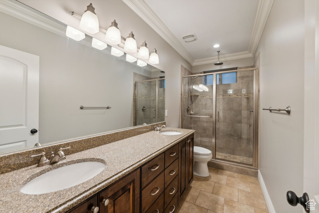 Bathroom featuring ornamental molding, a shower with door, vanity, and toilet