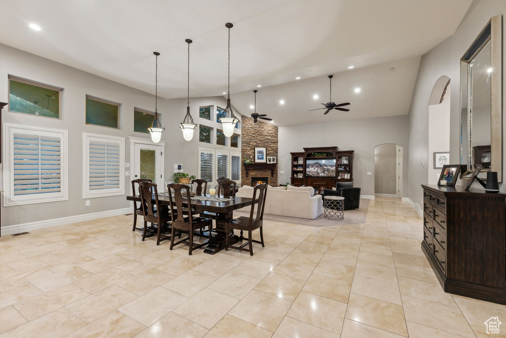 Dining space featuring high vaulted ceiling, ceiling fan, light tile patterned flooring, and a fireplace