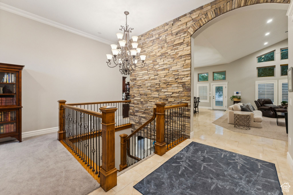 Hall featuring an inviting chandelier, crown molding, and light tile patterned floors