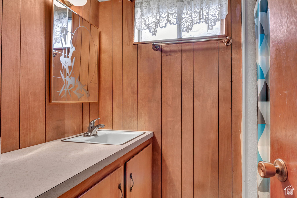 Bathroom with a healthy amount of sunlight, vanity, and wood walls