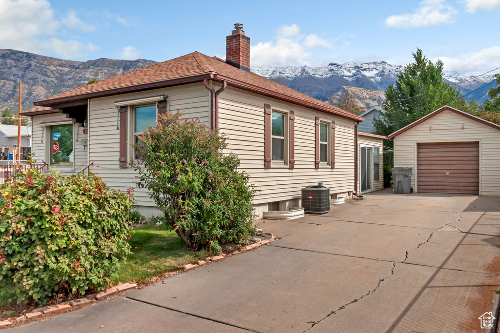 View of side of property featuring a mountain view, central AC unit, an outdoor structure, and a garage