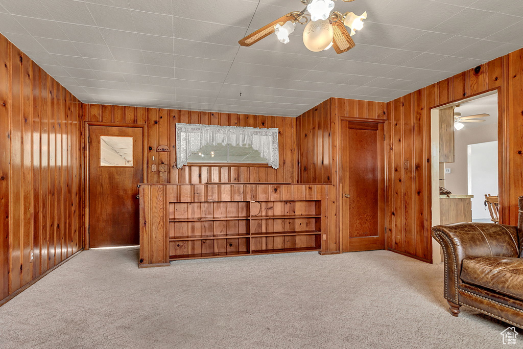 Sitting room with light carpet, wood walls, and ceiling fan