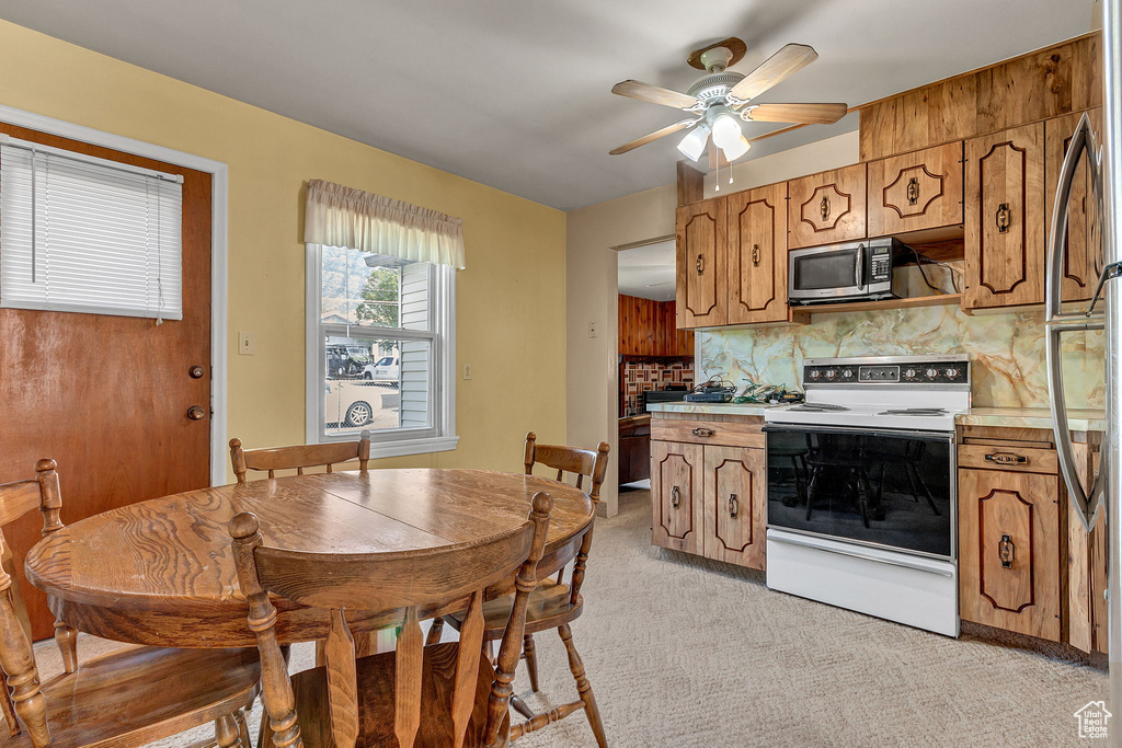 Kitchen with light carpet, stainless steel appliances, ceiling fan, and decorative backsplash