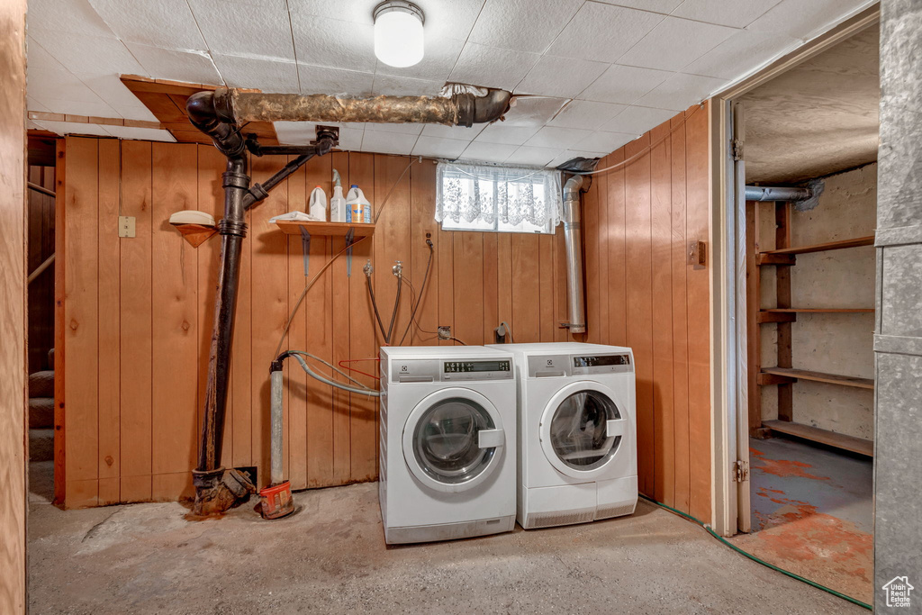 Laundry room with wooden walls and independent washer and dryer