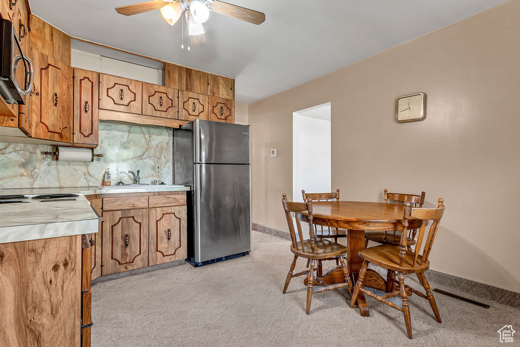 Carpeted dining space with ceiling fan and sink