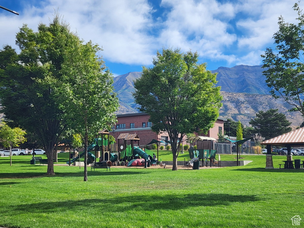 Surrounding community with a playground, a mountain view, a gazebo, and a lawn