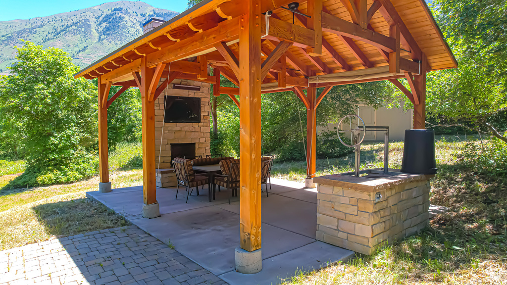 View of patio / terrace featuring a mountain view, an outdoor stone fireplace, and a gazebo