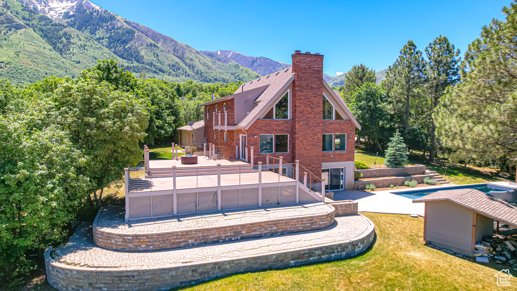 Back of house featuring a swimming pool side deck with mountain view, a yard, and a patio