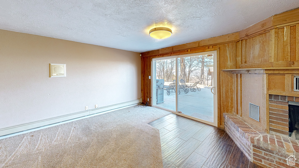 Unfurnished living room with a brick fireplace, a textured ceiling, and hardwood / wood-style flooring