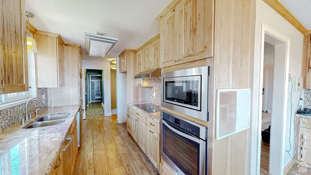 Kitchen featuring light wood-type flooring, appliances with stainless steel finishes, tasteful backsplash, and sink