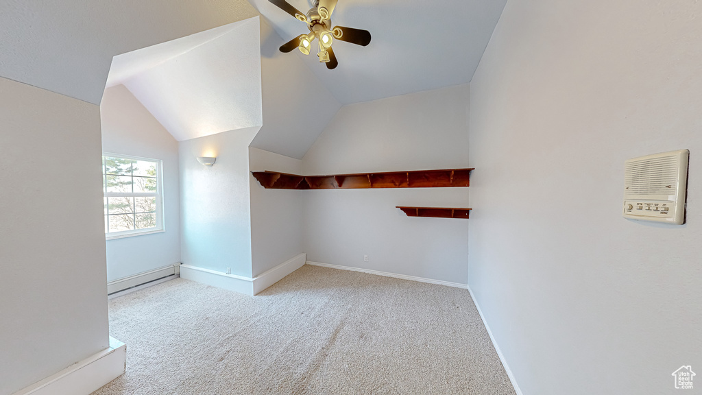 Additional living space with ceiling fan, light colored carpet, baseboard heating, and lofted ceiling