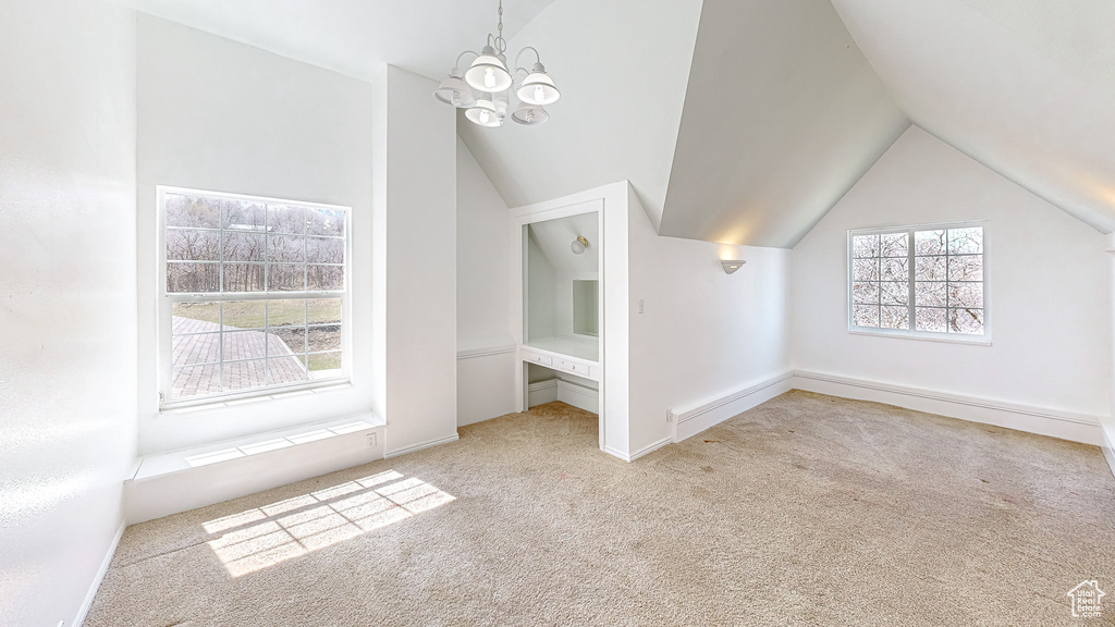 Additional living space featuring light carpet, lofted ceiling, and a chandelier