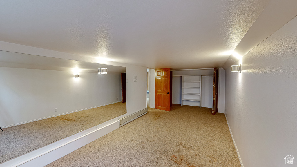 Basement featuring carpet floors, a textured ceiling, and a baseboard heating unit